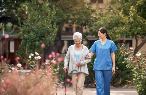 Pflegefachkraft unternimmt mit Seniorin einen Spaziergang